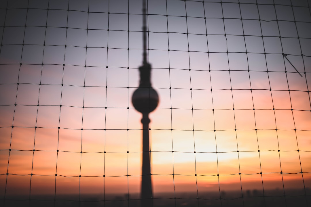 silhouette photo of hanging decor behind chain link fence at golden hour