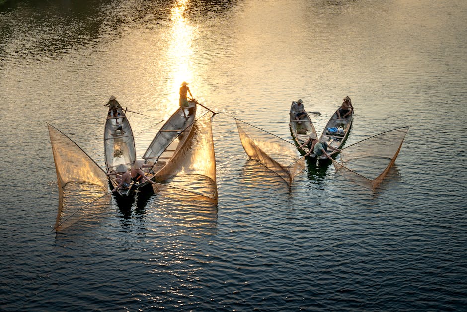 From above of anonymous men in boats fishing with nets in rippled ocean with shiny aqua in evening