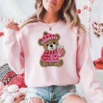 Woman wearing a pink sweater featuring a bear holding a coffee cup, decorated with hearts.