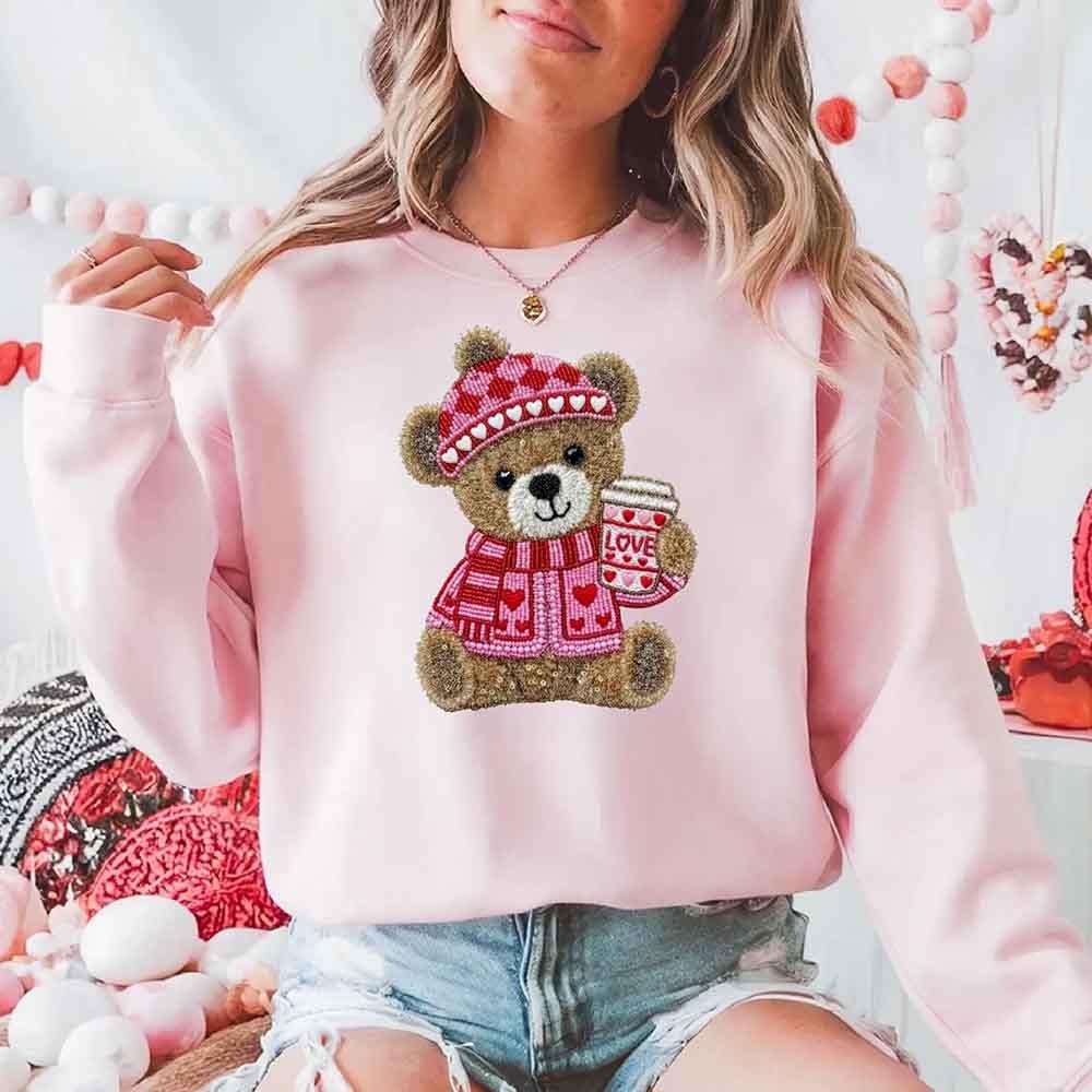 full-1973.jpg Woman wearing a pink sweater featuring a bear holding a coffee cup, decorated with hearts.